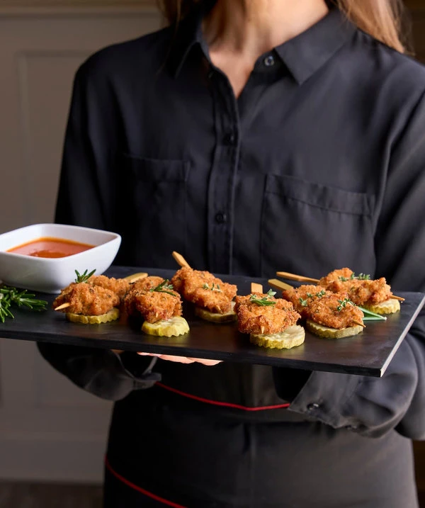 Woman in black outfit serving a Shrimp dish